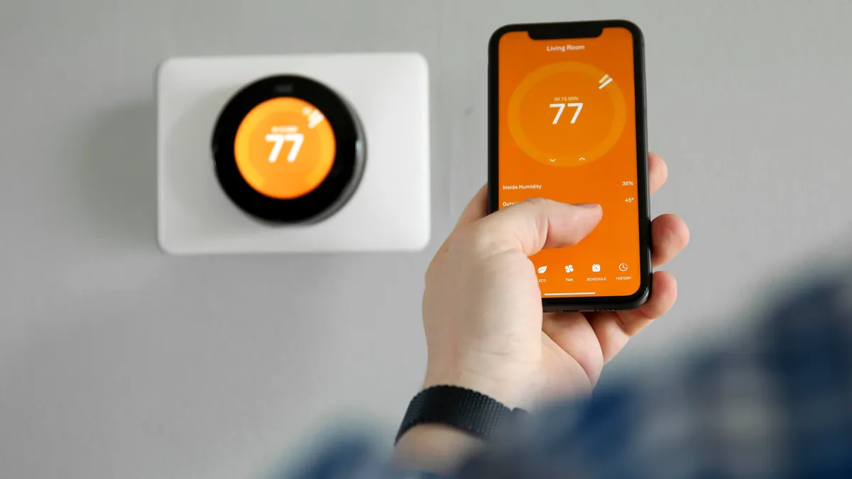 Homeowner controlling Nest smart thermostat from phone app